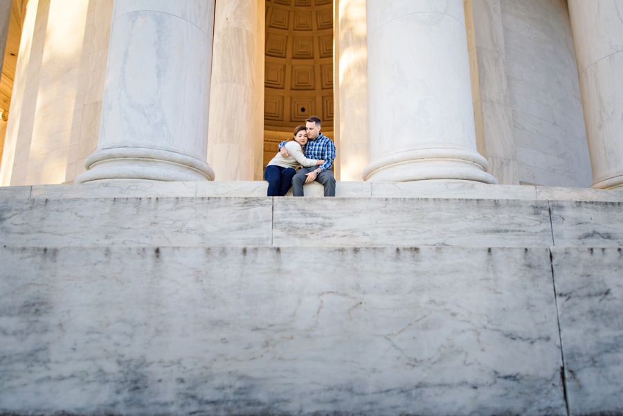 A newly engaged couple holding each other between the columns of the lincoln memorial in DC.